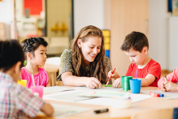 An Early Years Educator painting with children at ISR Kindergarten Neuss